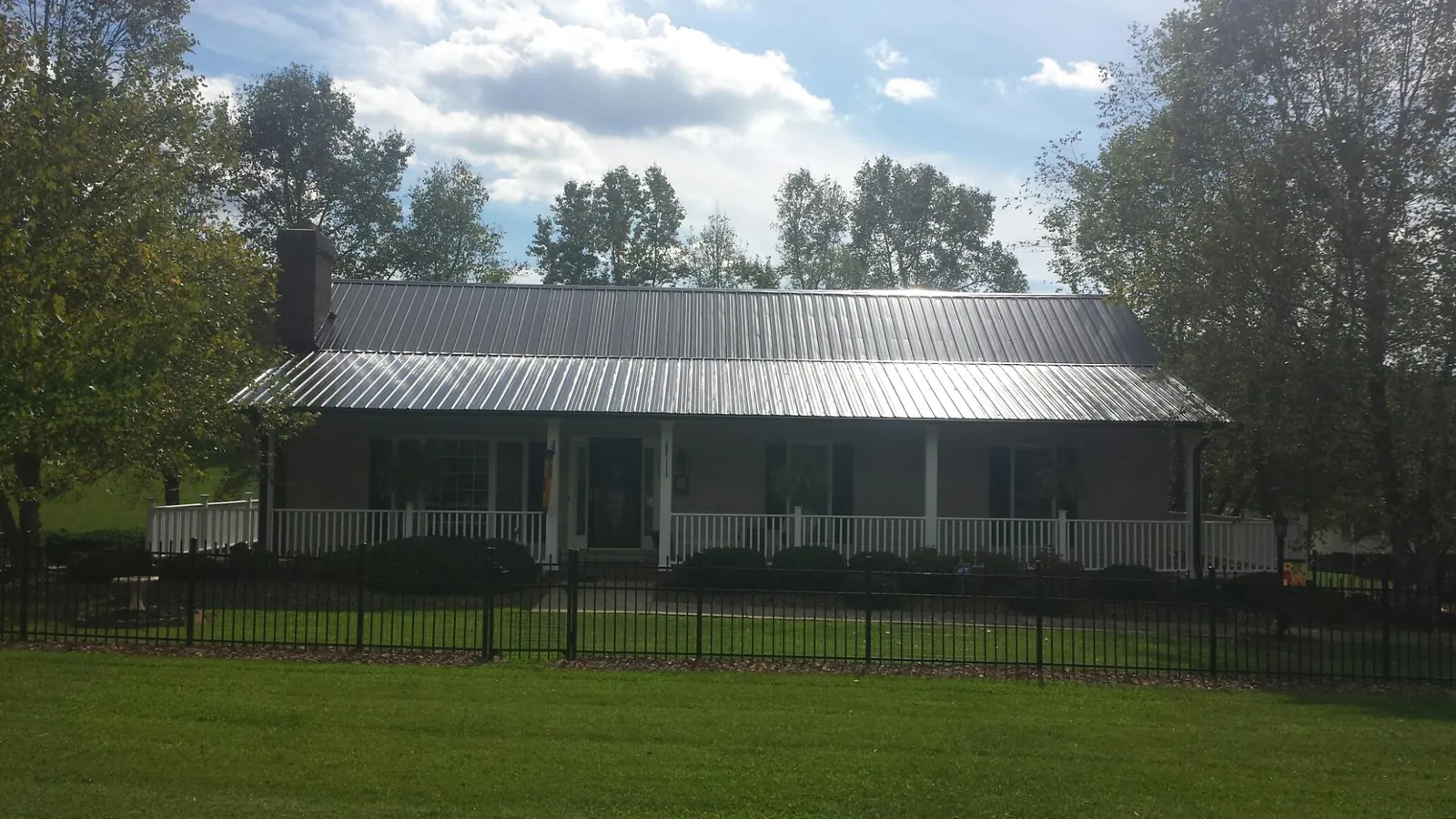 Gray metal roof on a brick ranch with a full width front porch — Gutter Guard Installation work by our crew in Attica