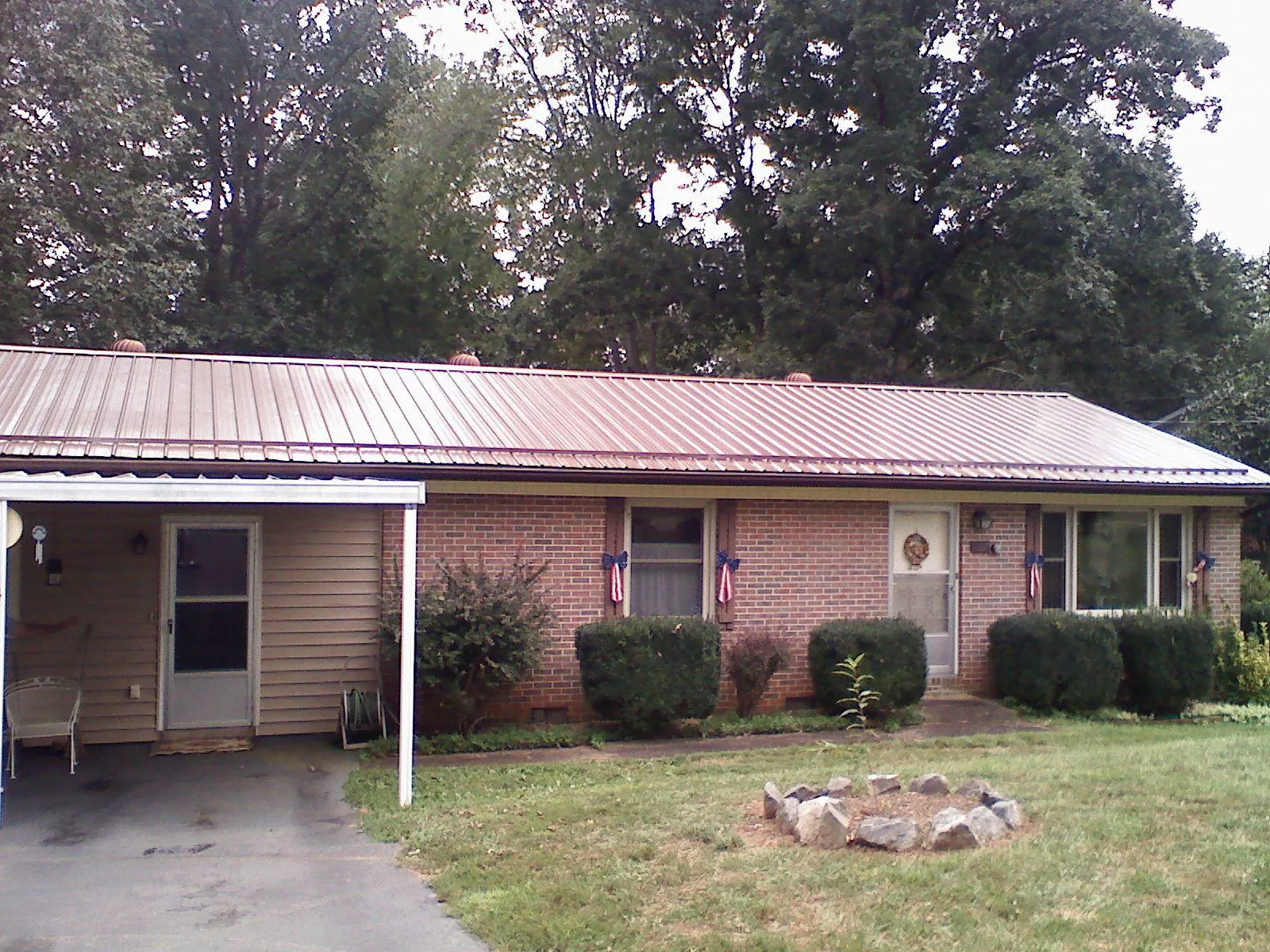 Bronze metal roof and carport on a brick ranch home — Roof Repair work by our crew in Attica