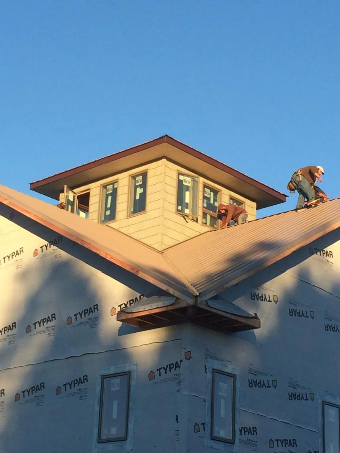 Roofers working around a rooftop cupola on a new metal roof at sunset — Roof Waterproofing in Attica by Roofing Brothers